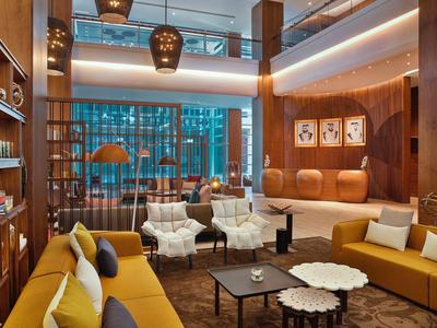 Modern hotel lounge with comfortable armchairs, sofas, and warm wood decor.