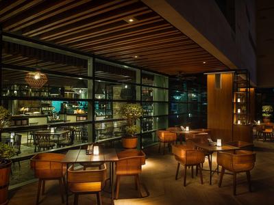 Cozy hotel lounge area with wooden tables, chairs, and warm lighting.