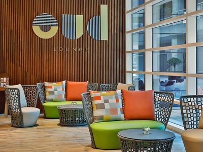 Espace salon moderne avec canapés colorés et coussins décoratifs dans le hall d'hôtel.