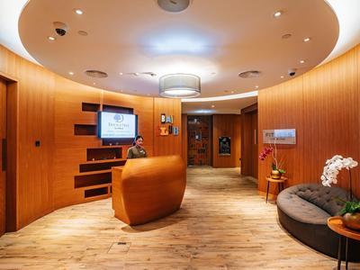 Réception d'hôtel moderne avec panneaux en bois et lumière de plafond ronde.