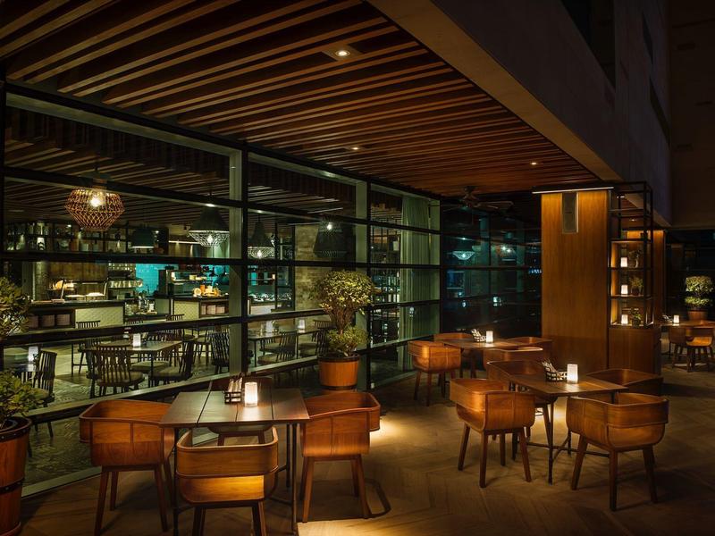 Bar d'hôtel confortable avec éclairage chaleureux, meubles en bois et étagères bien garnies.