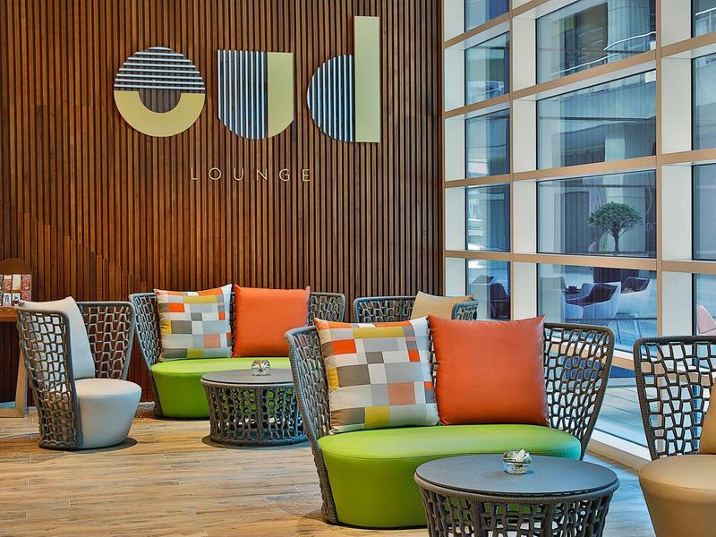 Espace salon moderne avec canapés colorés et coussins décoratifs dans le hall d'hôtel.