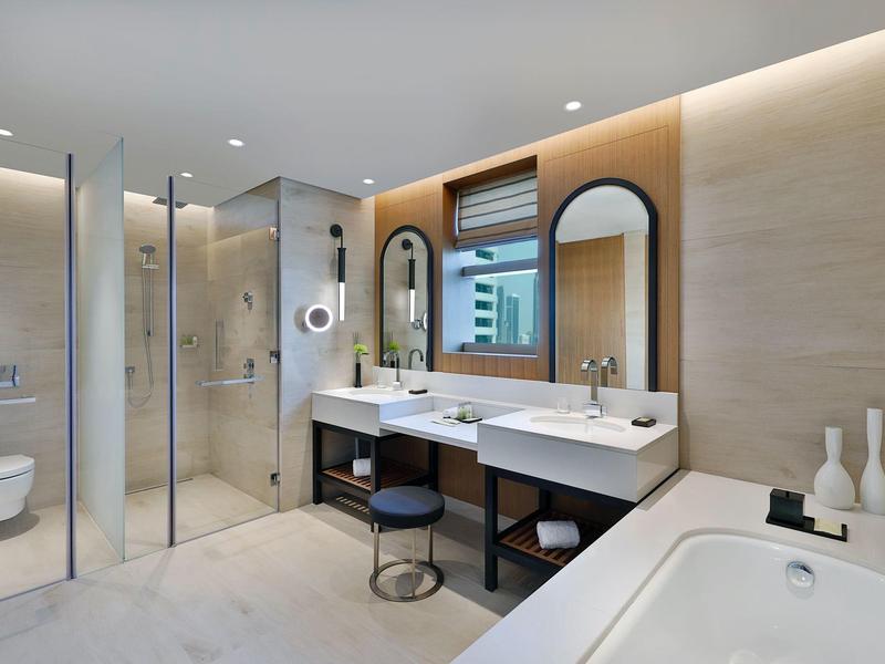 Salle de bain moderne avec deux lavabos, grande baignoire et douche à l'italienne en verre.