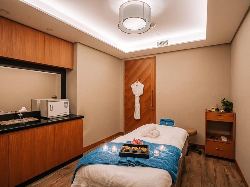 Salle de massage moderne avec table confortable, peignoir et accessoires disposés.