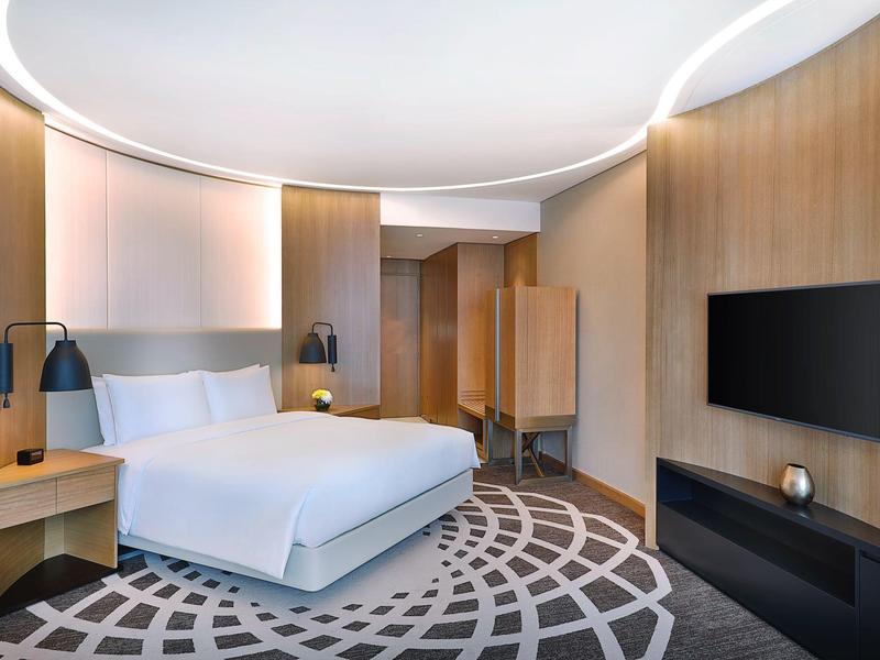 Chambre d'hôtel moderne avec lit double, TV, cheminée et panneaux en bois.