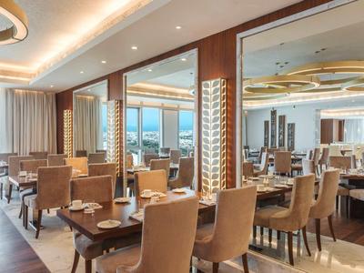 Restaurante moderno de hotel con sillas elegantes y grandes ventanas con vistas a la ciudad.