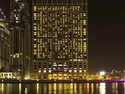 Verlicht hotelgebouw 's nachts met weerspiegelingen op het water.
