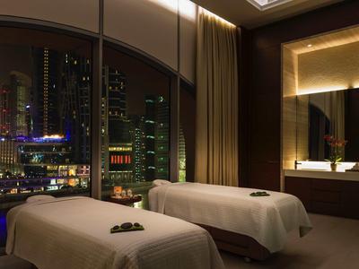 Luxe spa kamer met twee massagetafels en uitzicht op de stad 's nachts.