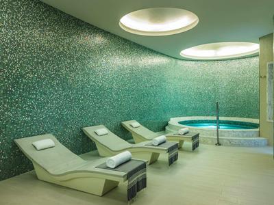 Modern ontspanningsruimte met ligstoelen en een mozaïek zwembad in het wellnessgedeelte.