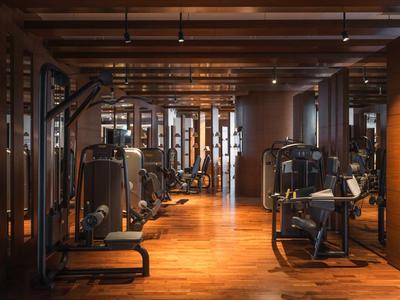 Interior de un gimnasio moderno con suelo de madera y varias máquinas de entrenamiento