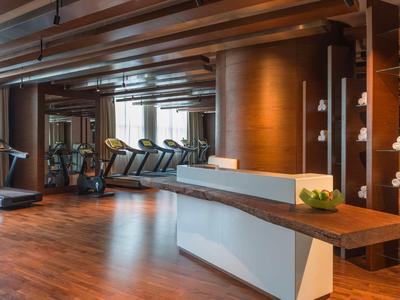 Gimnasio moderno con cintas de correr, equipos y suelo de madera cálido en un hotel.