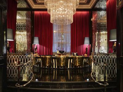 Elegante restaurante de hotel con un gran candelabro, cortinas de terciopelo rojo y mesas elegantes.