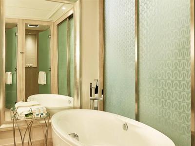 Elegante badkuip met glazen douche en grote spiegel in een lichte badkamer.