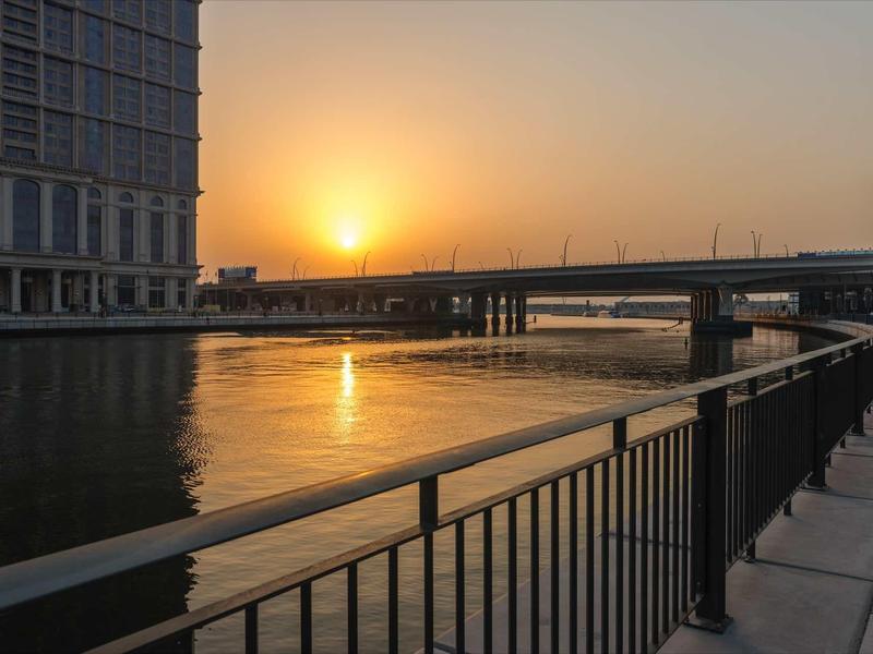 Zonsondergang boven een rivier met brug en reling op de voorgrond
