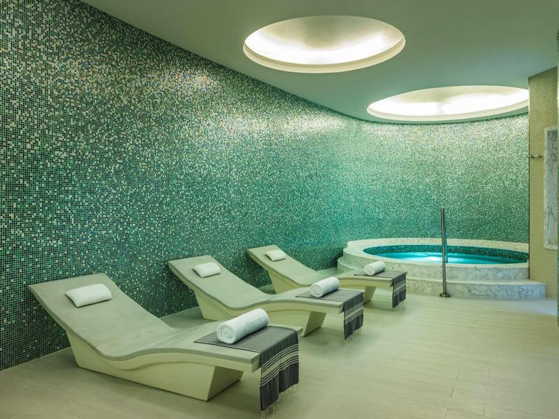 Modern ontspanningsruimte met ligstoelen en een mozaïek zwembad in het wellnessgedeelte.