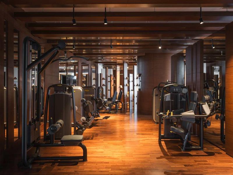 Moderne sportschool met houten vloer en verschillende fitnessapparaten in warm licht.