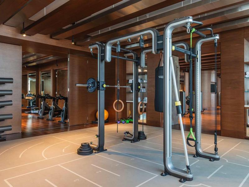 Moderne hotelfitnessruimte met apparatuur en houten plafonds.