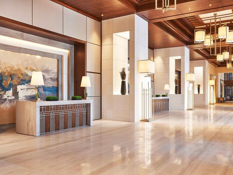 Lichte, moderne hotel lobby met houten plafond en groot schilderij aan de muur.