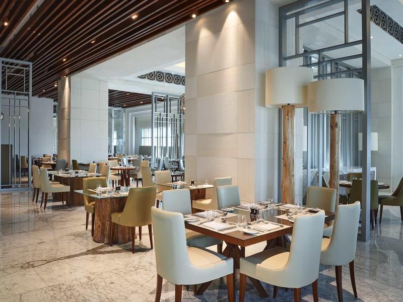 Elegant hotelrestaurant met moderne meubels en gedekte tafels in een lichte sfeer.