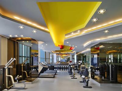 Gimnasio moderno con equipo de entrenamiento y acento amarillo brillante en el techo.