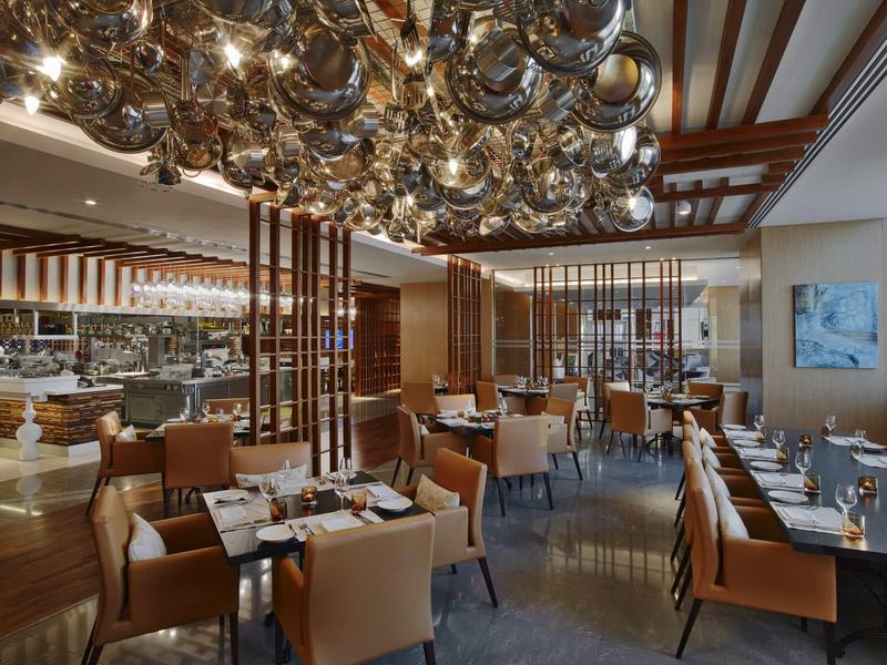 Ristorante elegante con poltrone marroni e lampade pendenti d'argento sul soffitto.