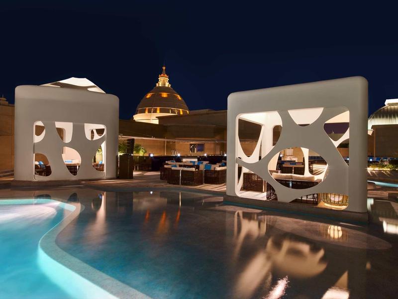 Area piscina illuminata con design moderno ed elementi architettonici di notte.