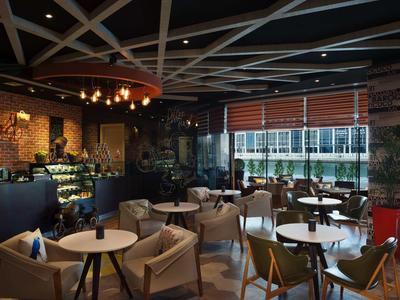 Przytulna kawiarnia z nowoczesnymi meblami i dużym oknem wpuszczającym naturalne światło.