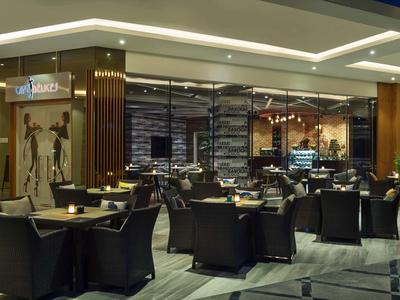 Lobby de hotel moderna con interior elegante y sillones negros alrededor de mesas.