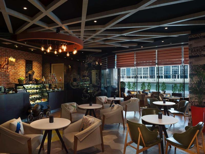 Acogedora zona de salón en hotel con sillas cómodas, mesas e iluminación decorativa.