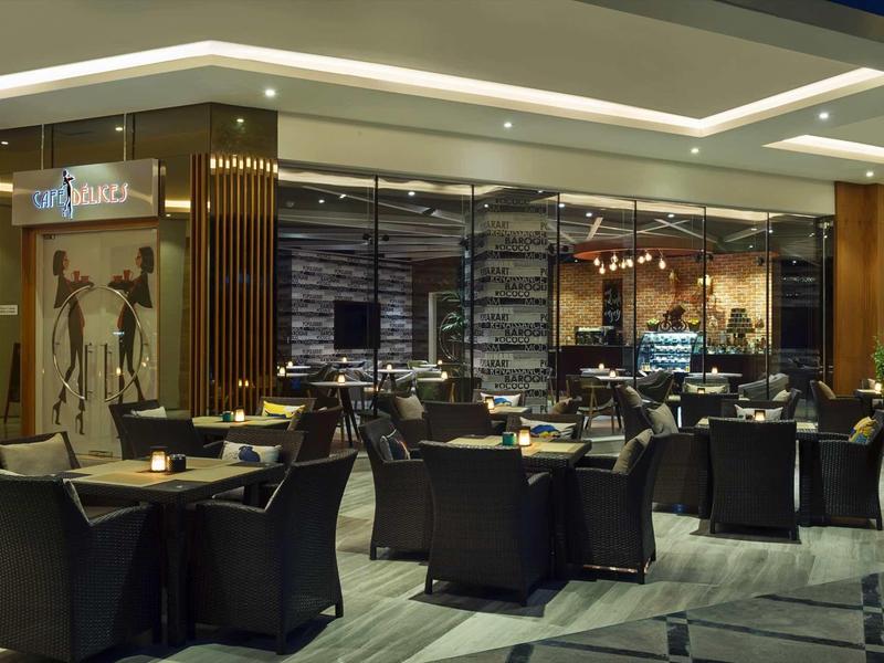 Lobby de hotel moderna con interior elegante y sillones negros alrededor de mesas.