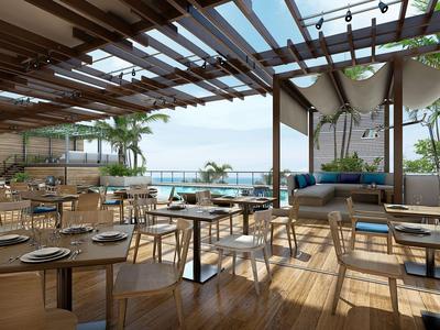 Zona ristorante luminosa sul tetto con pavimento in legno e vista diretta sul mare.