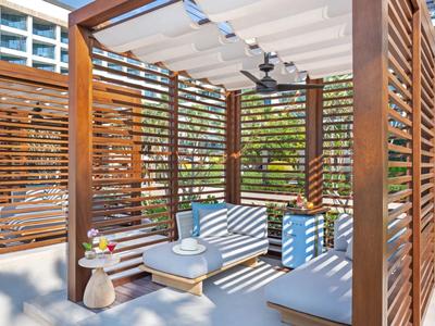 Moderní dřevěný pavilon s pohodlným posezením a stropními ventilátory u bazénu.