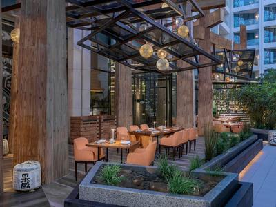 Area esterna moderna di un ristorante con colonne in legno e posti a sedere accoglienti.