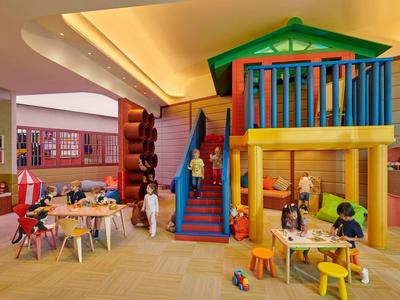 Barevná dětská herna v hotelu s lezeckou konstrukcí a posezením.