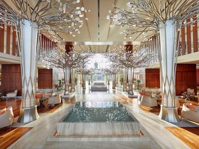 Luxuriöse Hotellobby mit hohen Decken, modernem Design und Wasserfontäne in der Mitte.