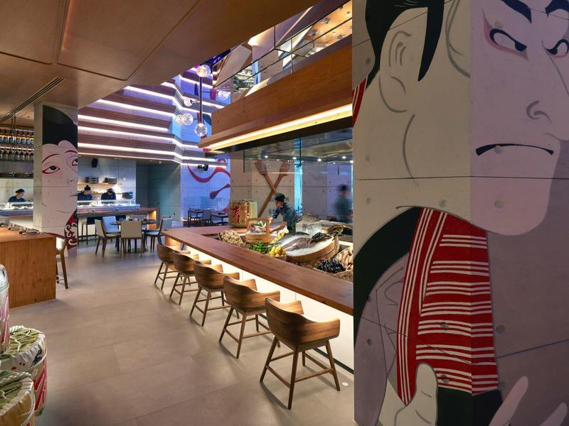 Moderní restaurace s dřevěným pultem, vysokými židličkami a nástěnným uměním s asijskou tváří.