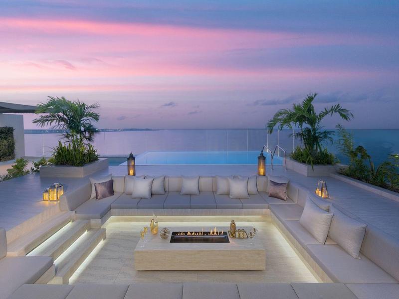 Luxusní venkovní posezení s ohništěm při západu slunce s výhledem na moře.