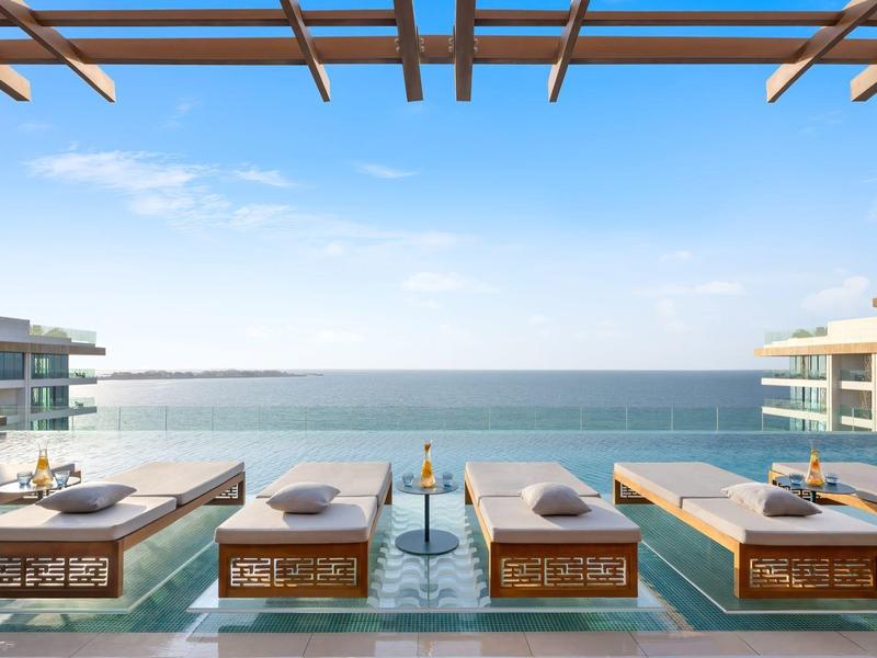 Luxusní lehátka na terase s výhledem na moře a modrou oblohu.