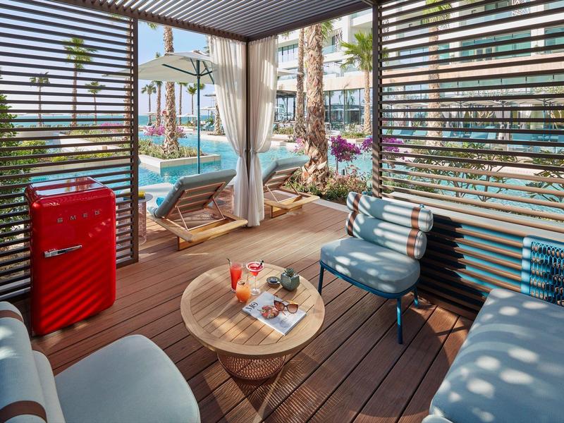 Pohodlná krytá venkovní část s posezením a výhledem na bazén a palmy.