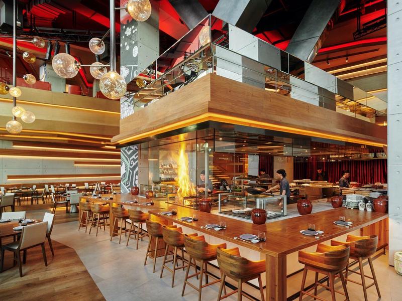 Moderní restaurace s dřevěnými a skleněnými prvky, velkými okny a stylovým osvětlením.