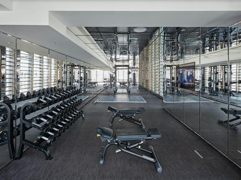 Moderní posilovna s činkami a lavicemi v hotelu.
