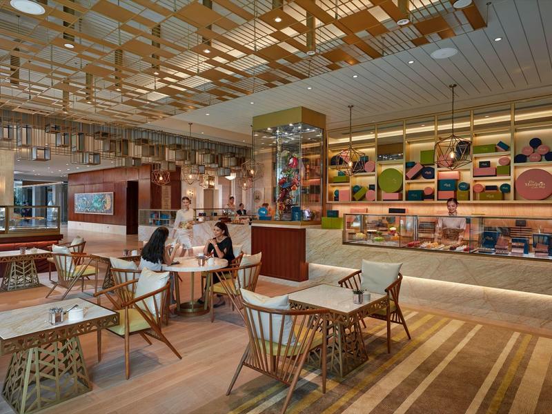 Moderní hotelová restaurace s dřevěnými židlemi, stoly a dekorativním stropem v teplých odstínech