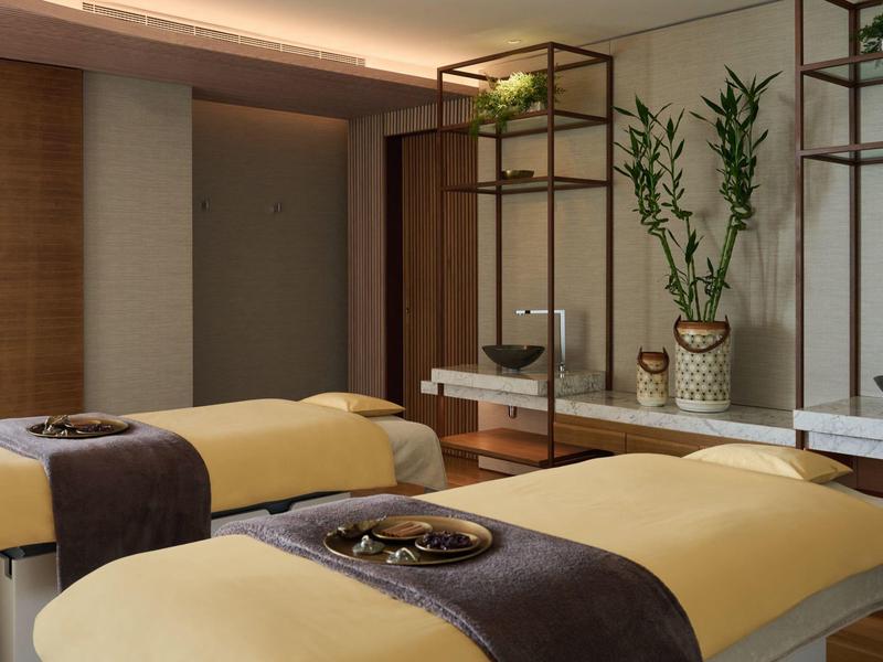 Moderní lázeňská místnost se dvěma masážními lehátky a stylovým dřevěným nábytkem.