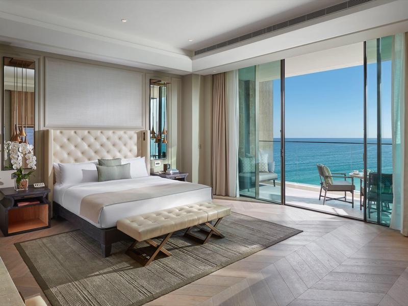 Světý hotelový pokoj s velkou postelí a balkonem s výhledem na moře.