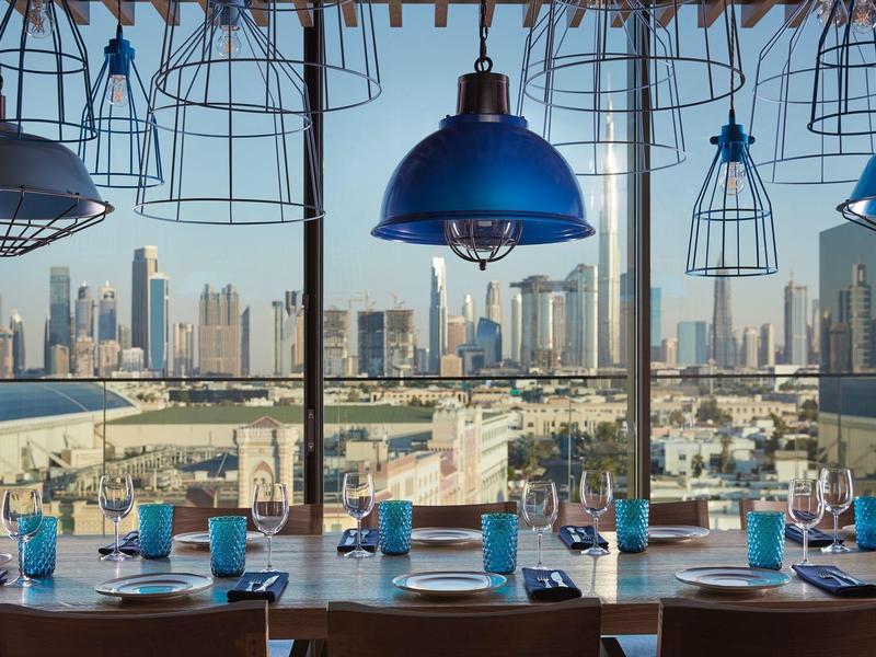 Restaurace se stolní výbavou a výhledem na městskou panorámu přes den