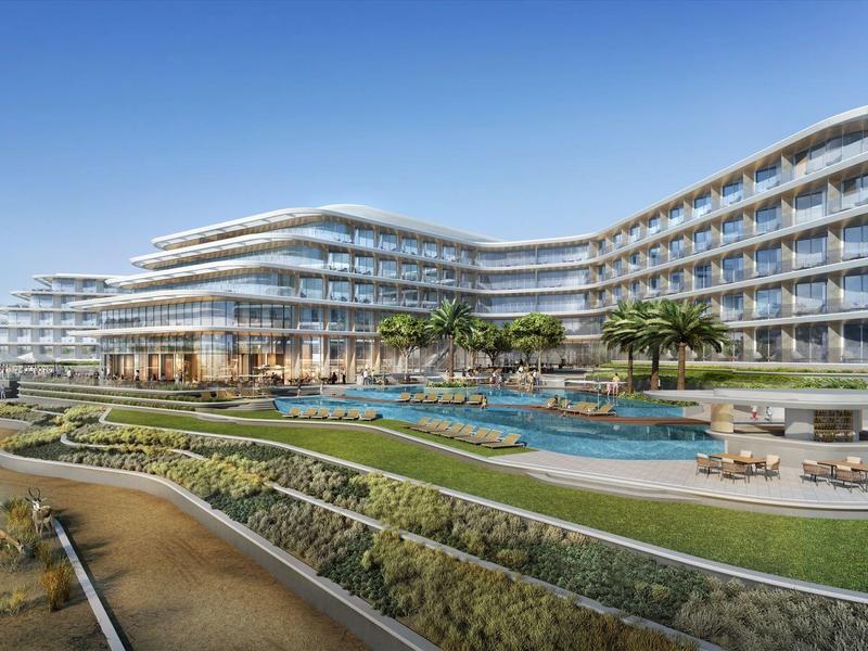 Modern, expansive hotel with large glass facades and green outdoor areas with pools.