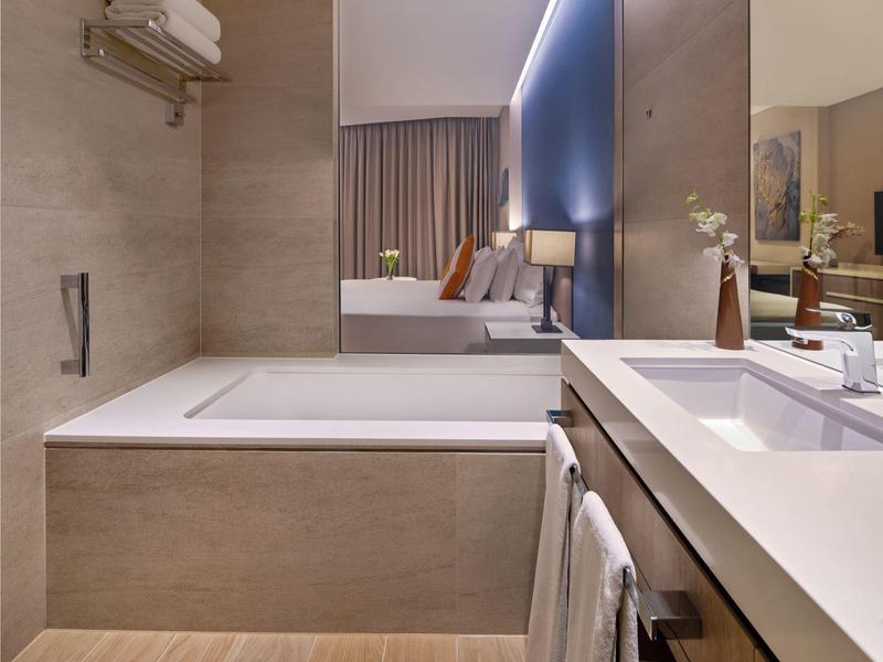 Modern bathroom with bathtub, sink, and large mirror in neutral tones.