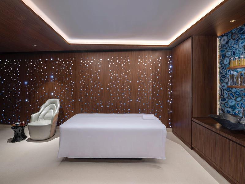 Modern eingerichteter Raum mit weißem Bett, brauner Wand und dekorativer blauer Wandgestaltung.