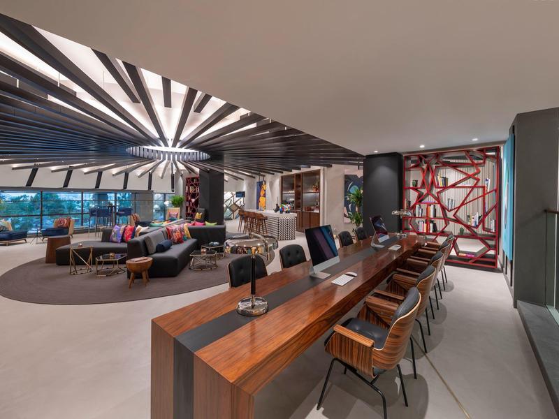 Moderner, offener Wohnraum mit Holzbar, Lederstühlen, runden Teppichen und großen Fenstern.