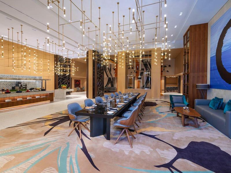 Modernes Esszimmer mit großem schwarzem Tisch, blauen Stühlen, Teppich und außergewöhnlichen Hängeleuchten.